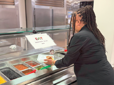 woman grabbing food from cafeteria line